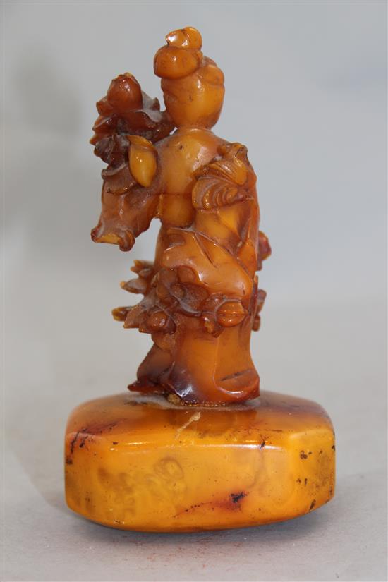 A Chinese egg yolk yellow amber figure of He Xiangu, 20th century, 14cm, glued repairs
